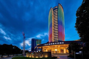 A hotel entrance with a modern design, featuring a curved facade and illuminated signage. - Four Points By Sheraton Liupanshui (Liupanshui)