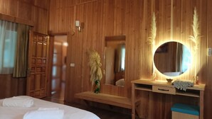 Una habitación de madera con una cama, un escritorio con espejo y un banco.