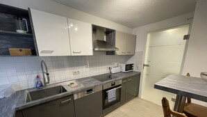 A modern kitchen with grey cabinets, a stainless steel sink, a microwave, and a built-in oven. - Fewo Reutlingen Metzstrasse (Reutlingen)