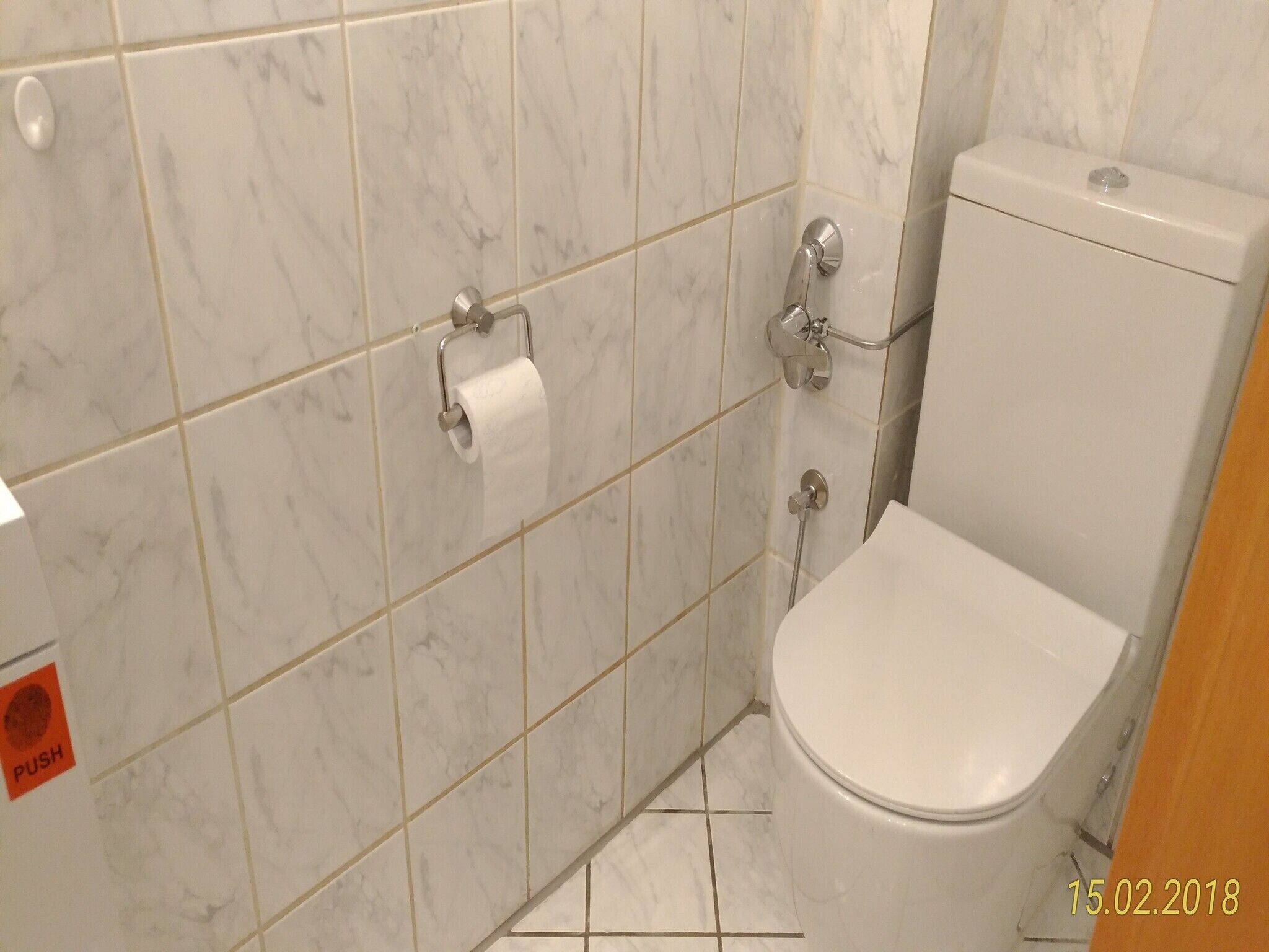 Un baño con inodoro, secador de manos y dispensador de toallas de papel.