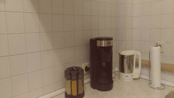 A kitchen with a coffee maker, a kettle, and spice containers.