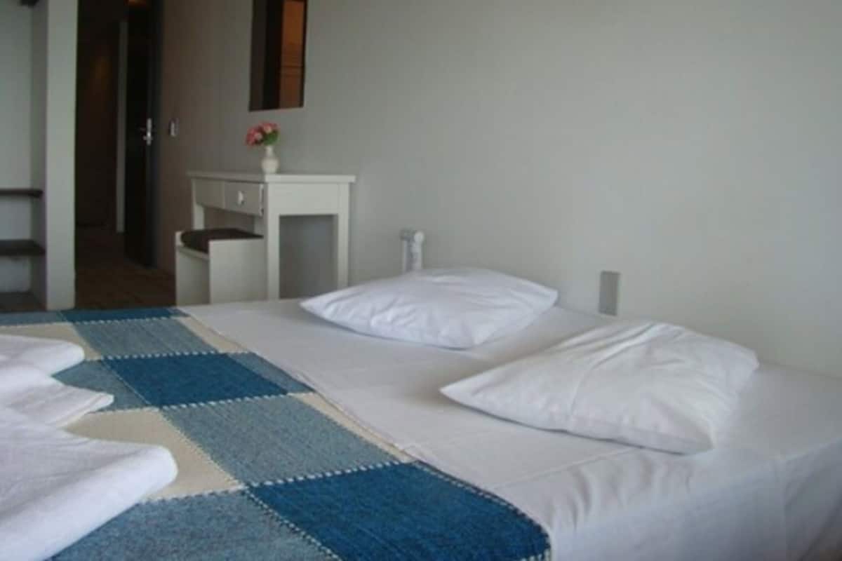 A hotel room with a bed, a bedside table, and a small desk with a chair.
