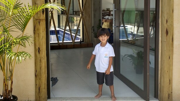 A wooden sign with "UBUNTU POUSA" above a doorway, a potted plant to the left, and a child standing in the doorway.