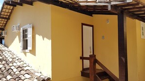 Un bâtiment jaune avec un escalier en bois et une porte.