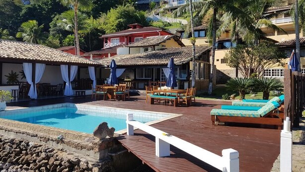 Un espace piscine doté d’une terrasse en bois, de chaises longues et de parasols.