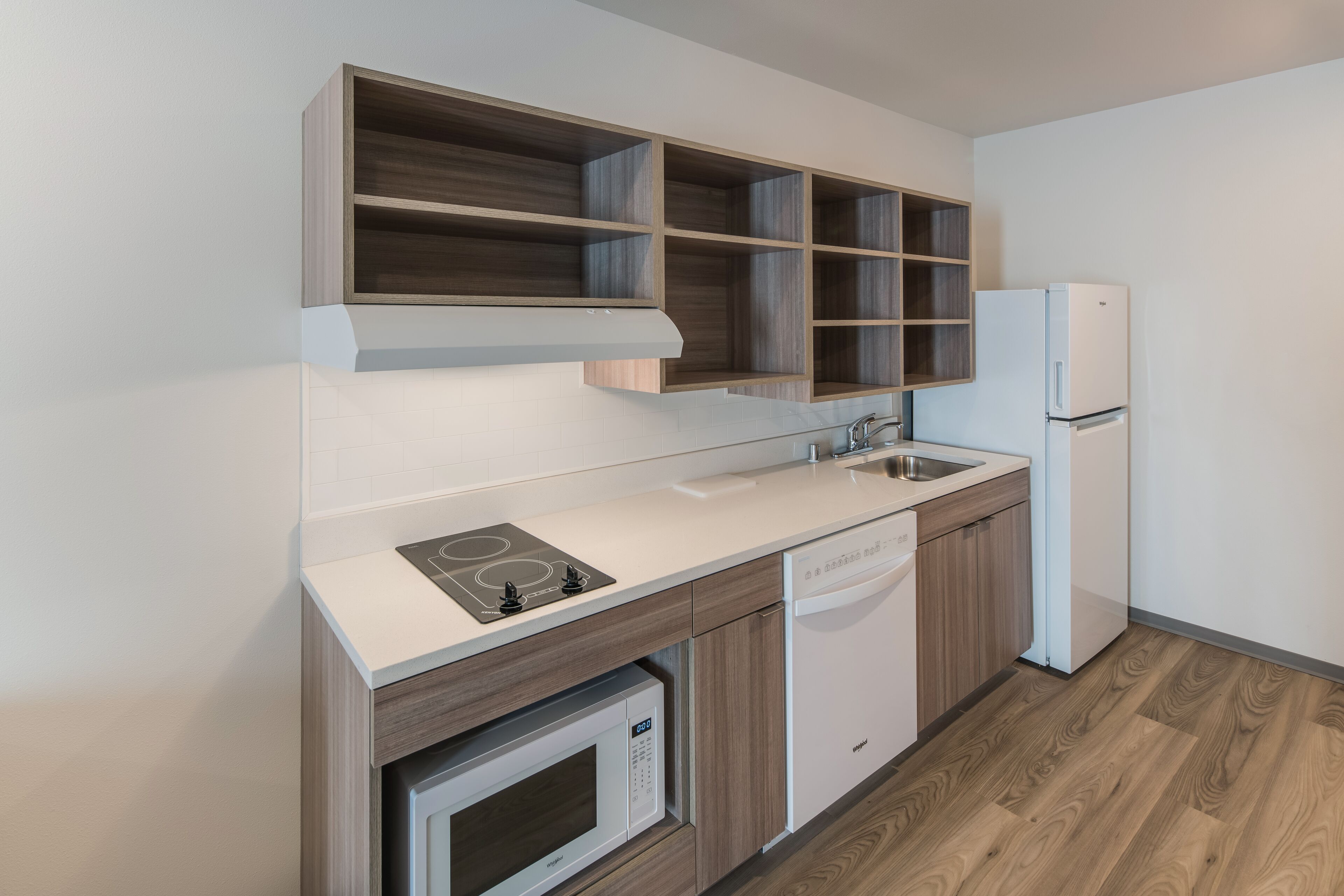 A modern kitchen with a built-in microwave, dishwasher, and a white refrigerator.