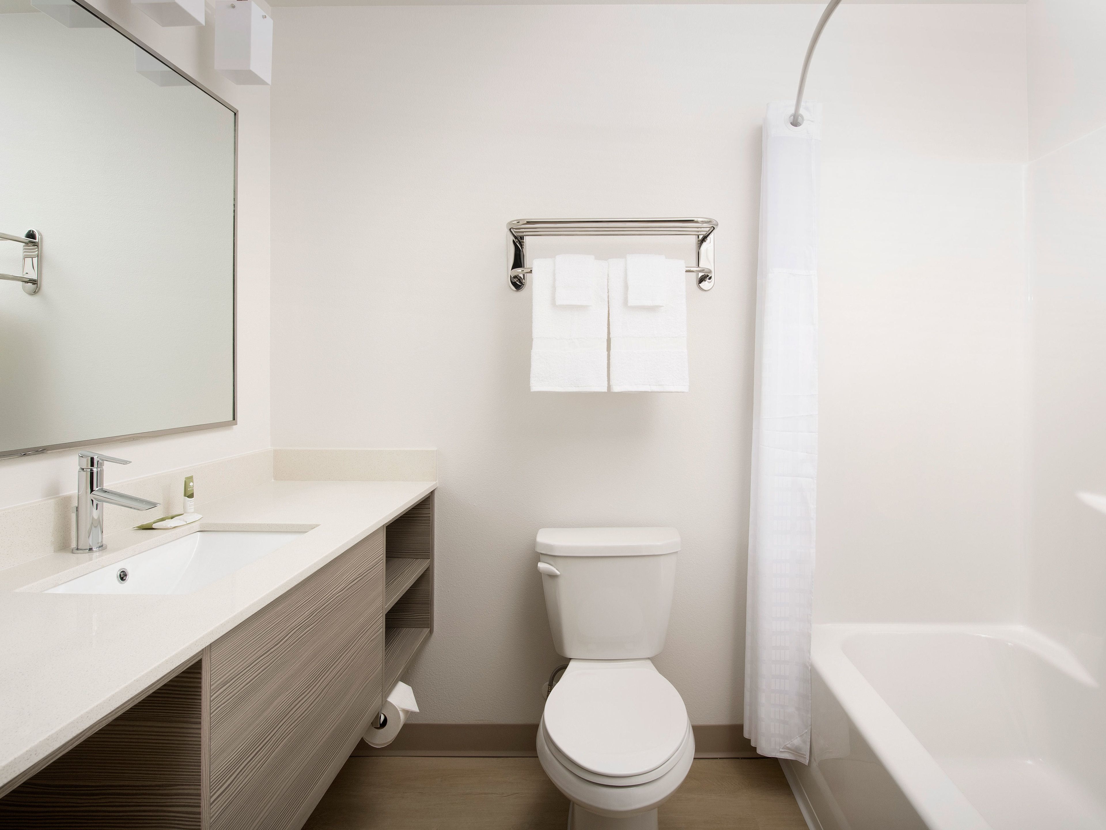 A modern bathroom with a white sink, mirror, toilet, and bathtub.