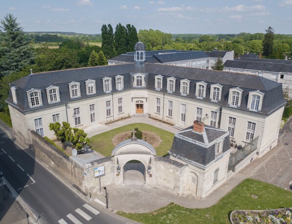 Een groot, historisch gebouw met een symmetrische gevel, meerdere ramen en een centrale ingang met een boog.