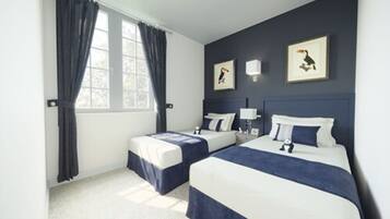 Una habitación de hotel con dos camas, una ventana con cortinas y obras de arte colgadas en la pared.
