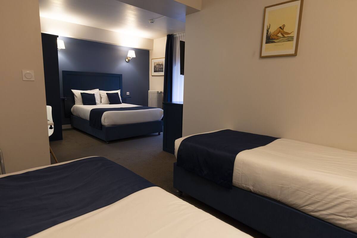 Una habitación de hotel con dos camas individuales, una cama grande y un escritorio.