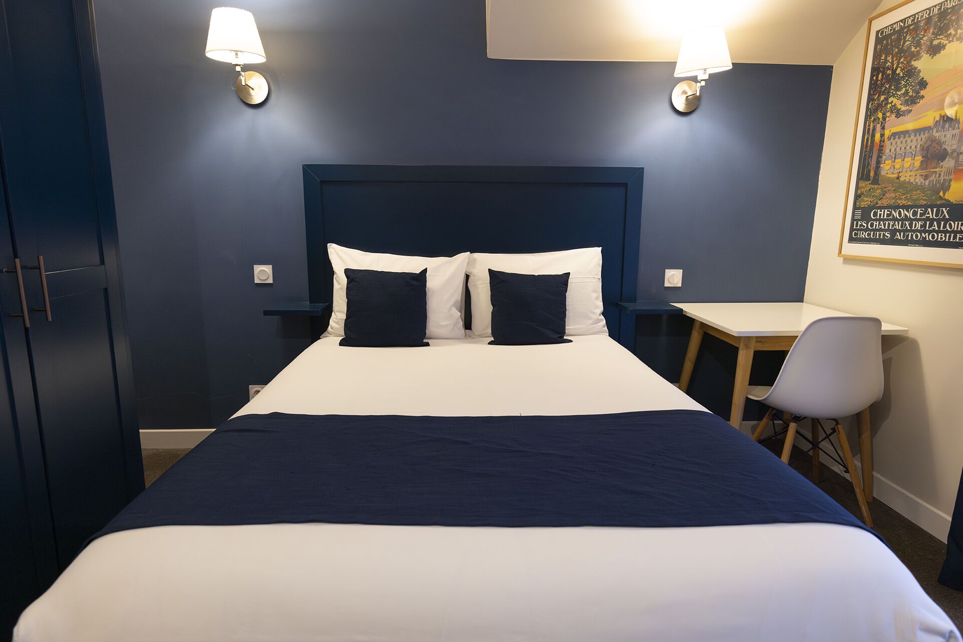 Une chambre d’hôtel avec un grand lit, deux lampes de chevet, un bureau et une chaise.