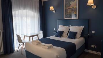 Une chambre d’hôtel avec un lit, des tables de chevet, un bureau et une chaise.