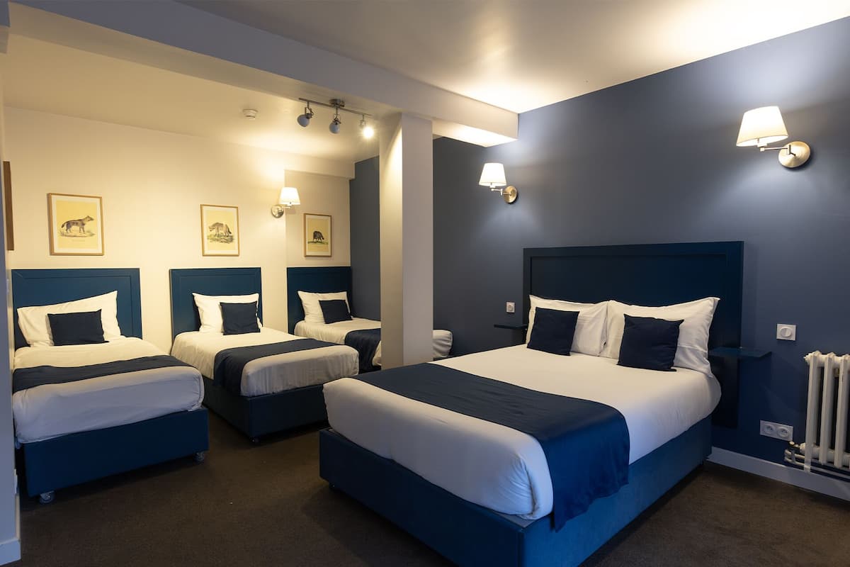Una habitación de hotel con una cama grande, dos camas más pequeñas y un área de estar.