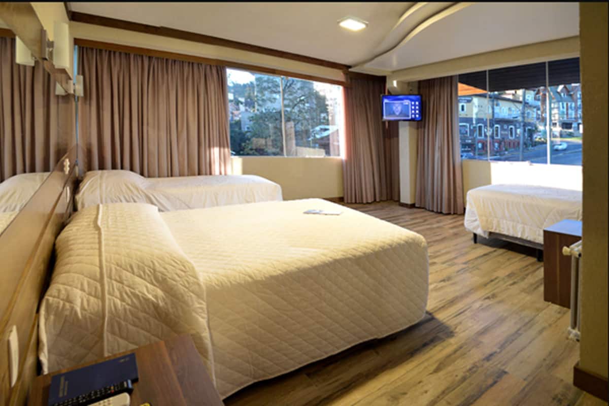 Habitación de hotel con dos camas, televisión y ventana con vista a la calle.
