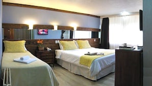 A hotel room with two single beds, a wooden headboard, a bedside table with a lamp, and a TV mounted on the wall. - Sky Centro Hotel & Spa (Gramado)