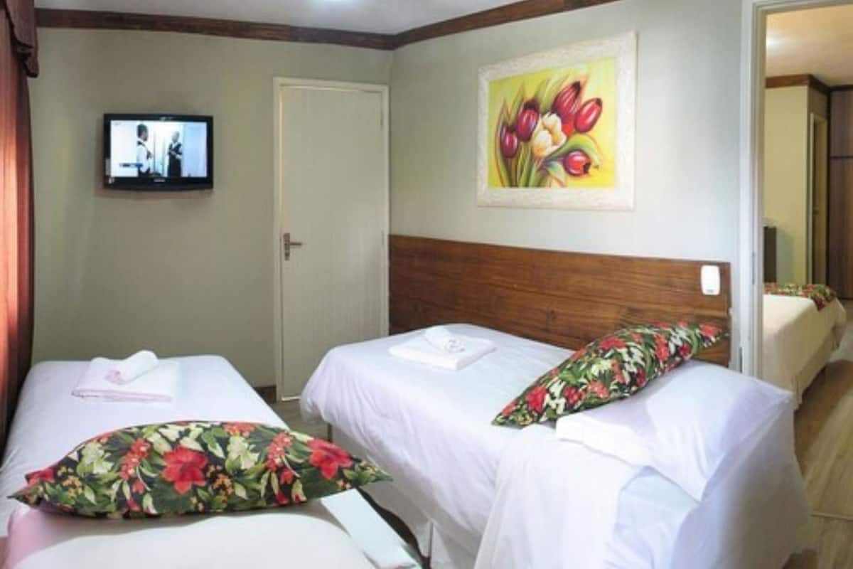 Habitación de hotel con dos camas, televisión y un cuadro en la pared.