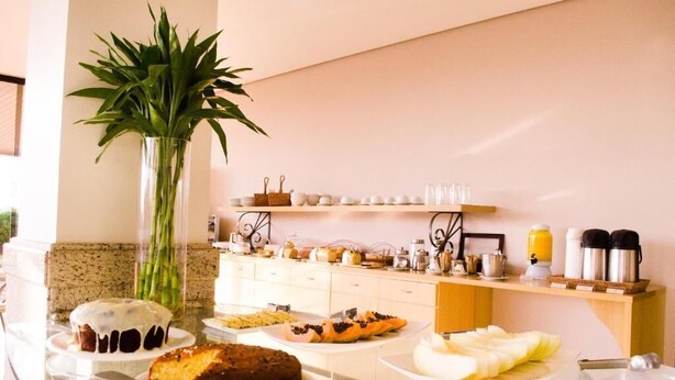 A buffet setup with various food items, a vase with green plants, and kitchen appliances on a counter.