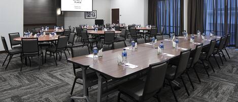 Un salón de conferencias con varias mesas, sillas y botellas de agua.
