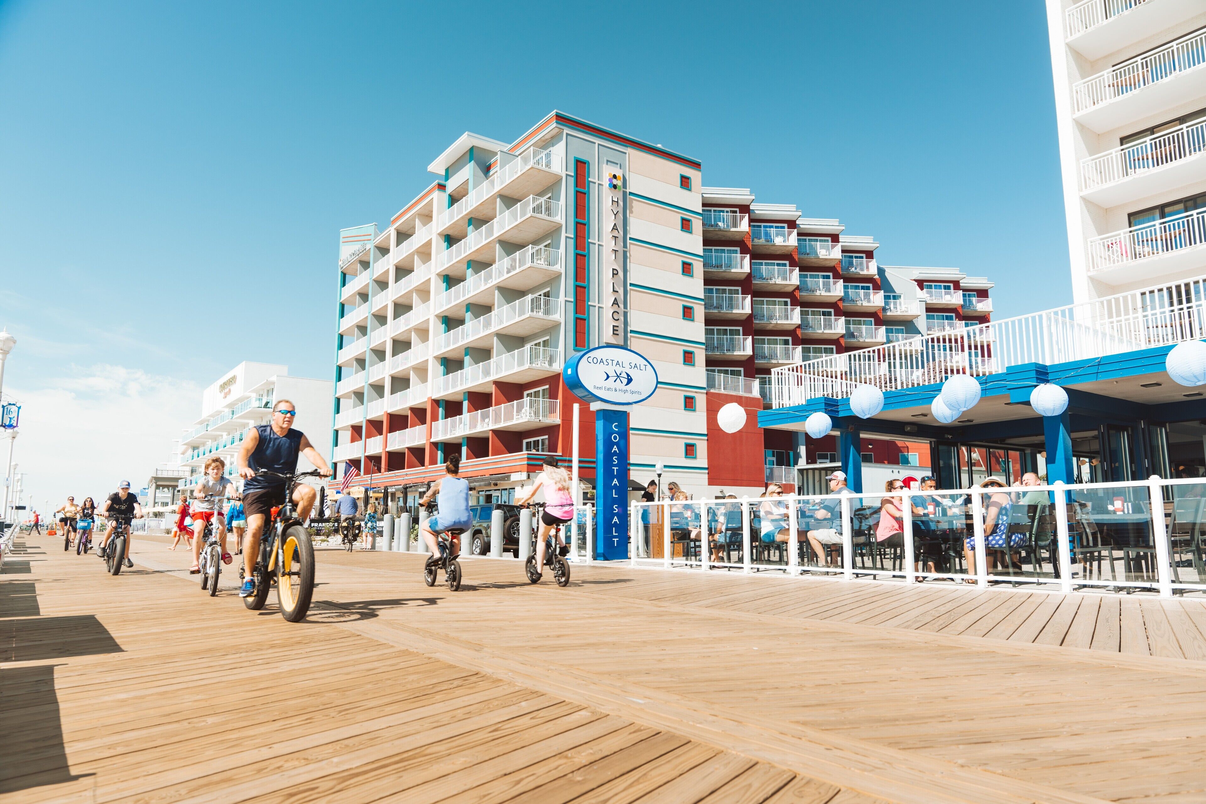 A coastal boardwalk with a sign for 'Coastal Salt' and 'Coastalsalt' buildings in the background.