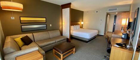 A hotel room with a bed, a sofa, a desk, and a chair.