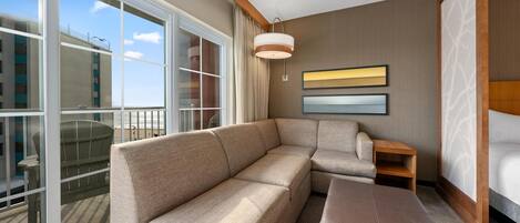 Una habitación de hotel moderna con un ventanal grande, un sofá, una silla y una cama.