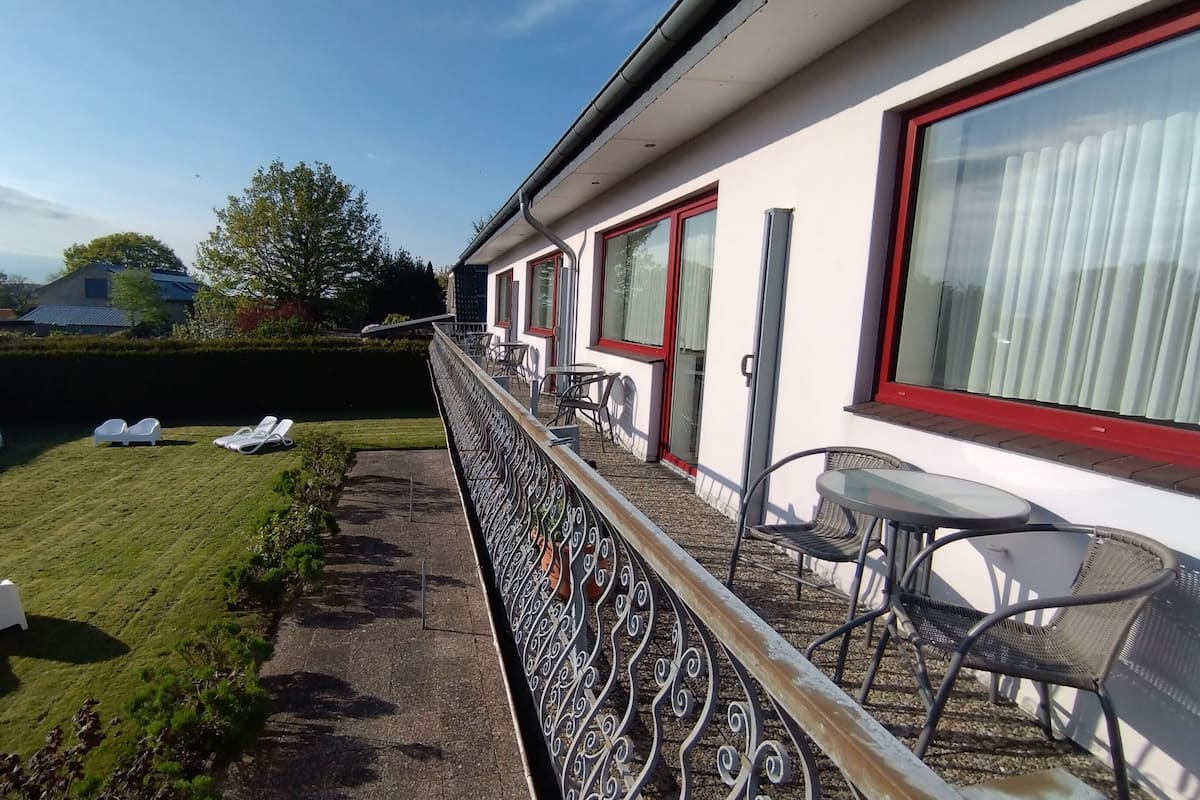 Une chambre d’hôtel avec balcon, un petit jardin et vue sur les environs.