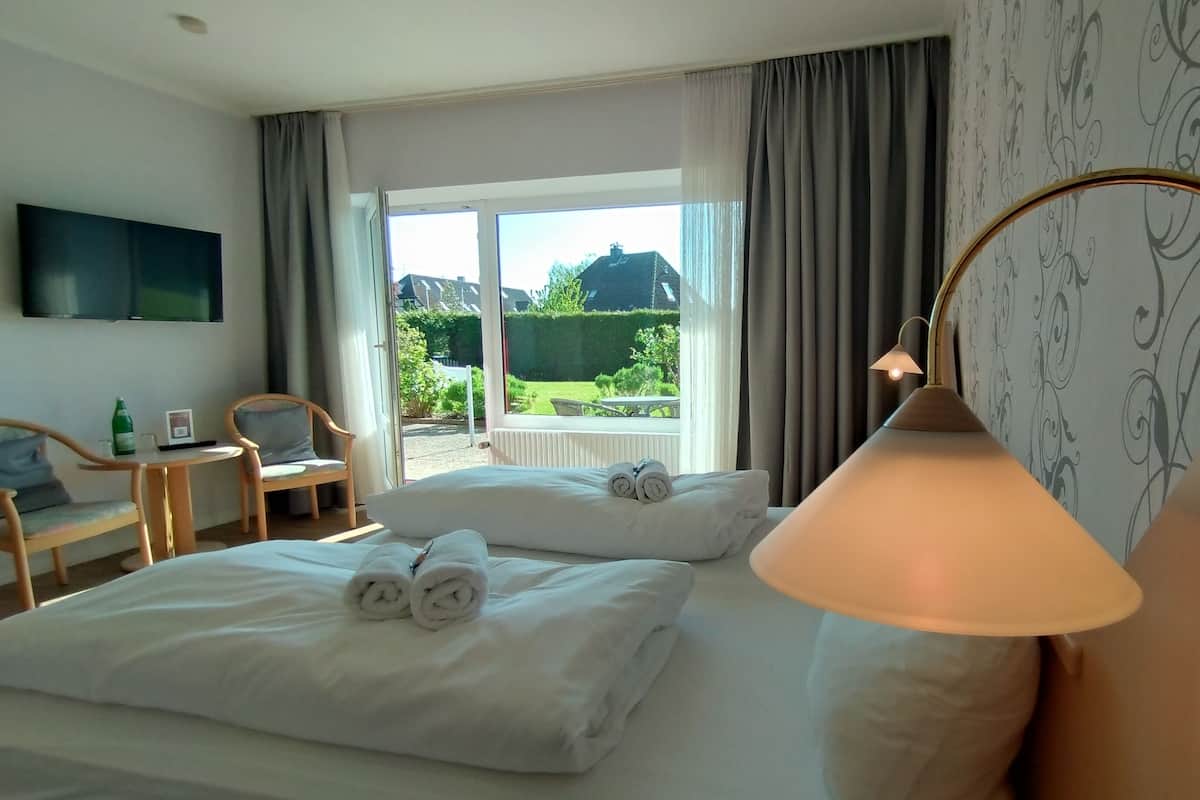 Une chambre d’hôtel avec deux lits, une télévision, une table avec des chaises et une vue sur l’extérieur.