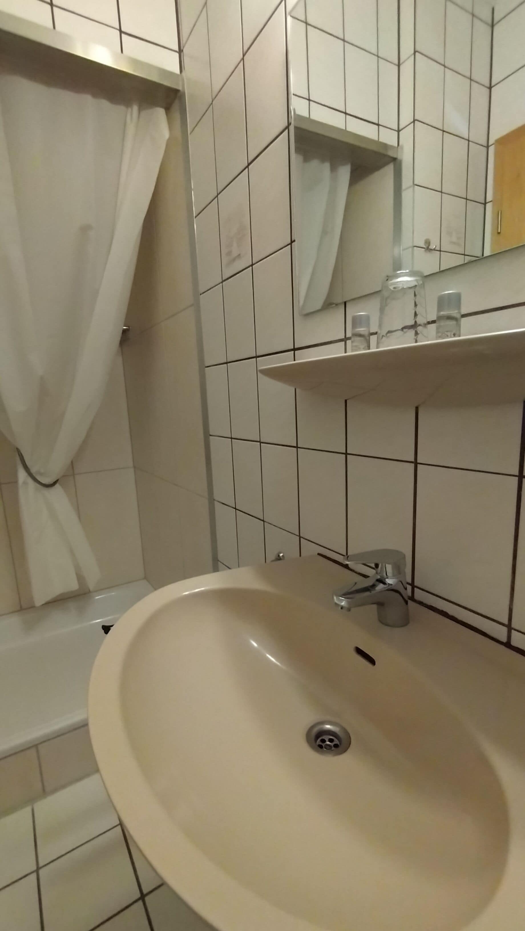 A bathroom with a sink, mirror, and tiled walls.