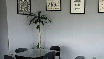 Un área de comedor moderna con una mesa de vidrio y sillas negras, rodeada de decoración mural inspiradora.