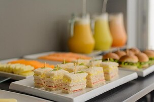 Un bufé con sándwiches, fruta y bebidas.