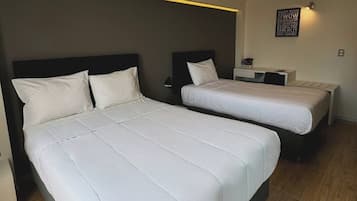 Une chambre double avec deux lits, un bureau et un luminaire fixé au mur.