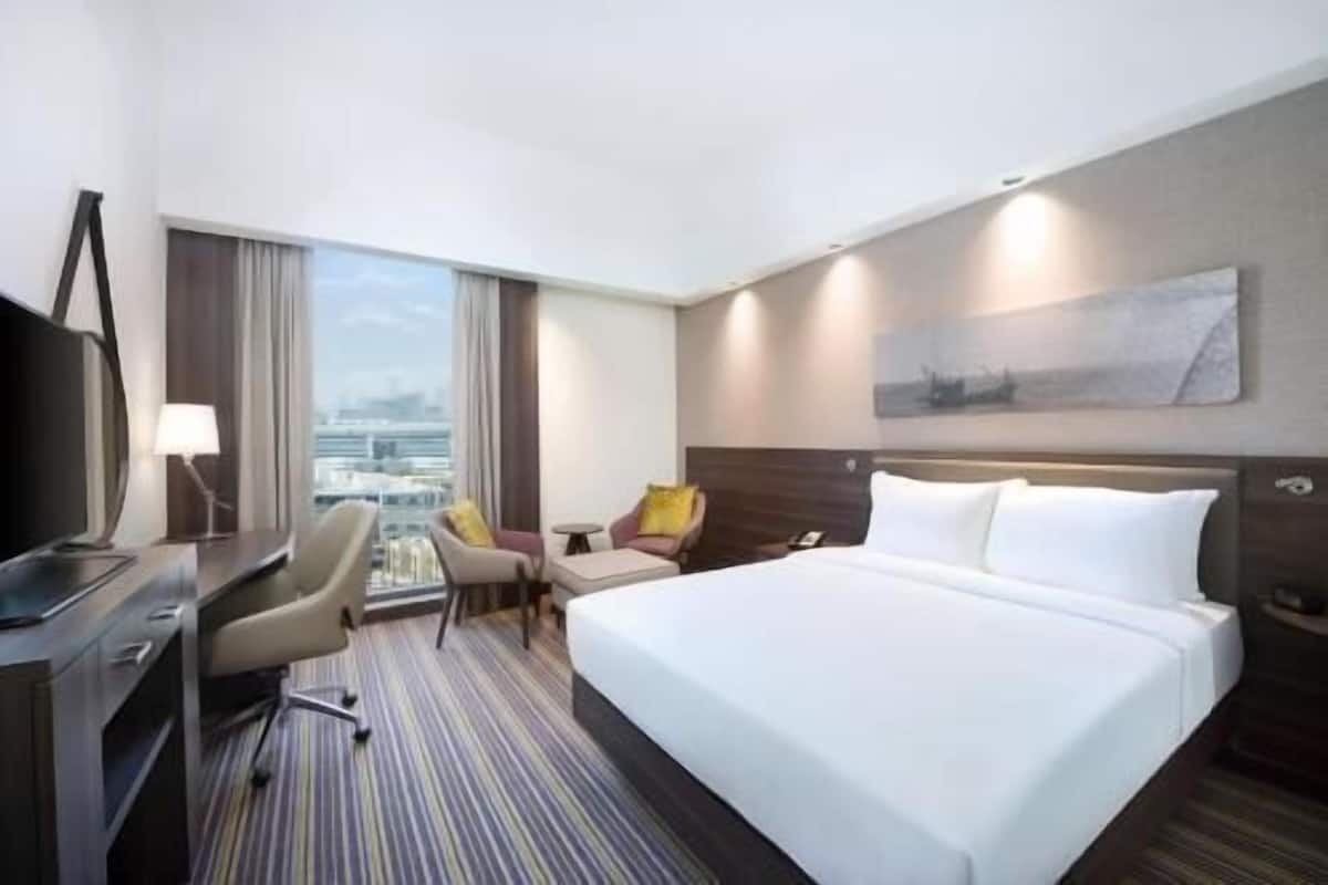 Une chambre d’hôtel avec un lit, un bureau, des chaises et une vue sur la ville.
