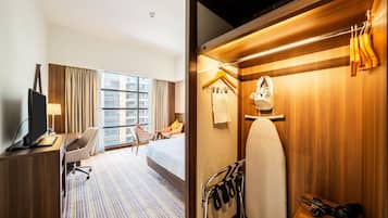 Habitación de hotel con cama, escritorio, silla y vistas a la ciudad.
