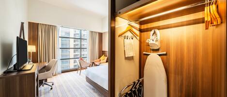 Habitación de hotel con cama, escritorio, silla y vistas a la ciudad.