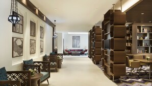 Een moderne hotel lobby met een centraal zitgedeelte, een grote boekenkast en kunstwerken in lijsten aan de muren.