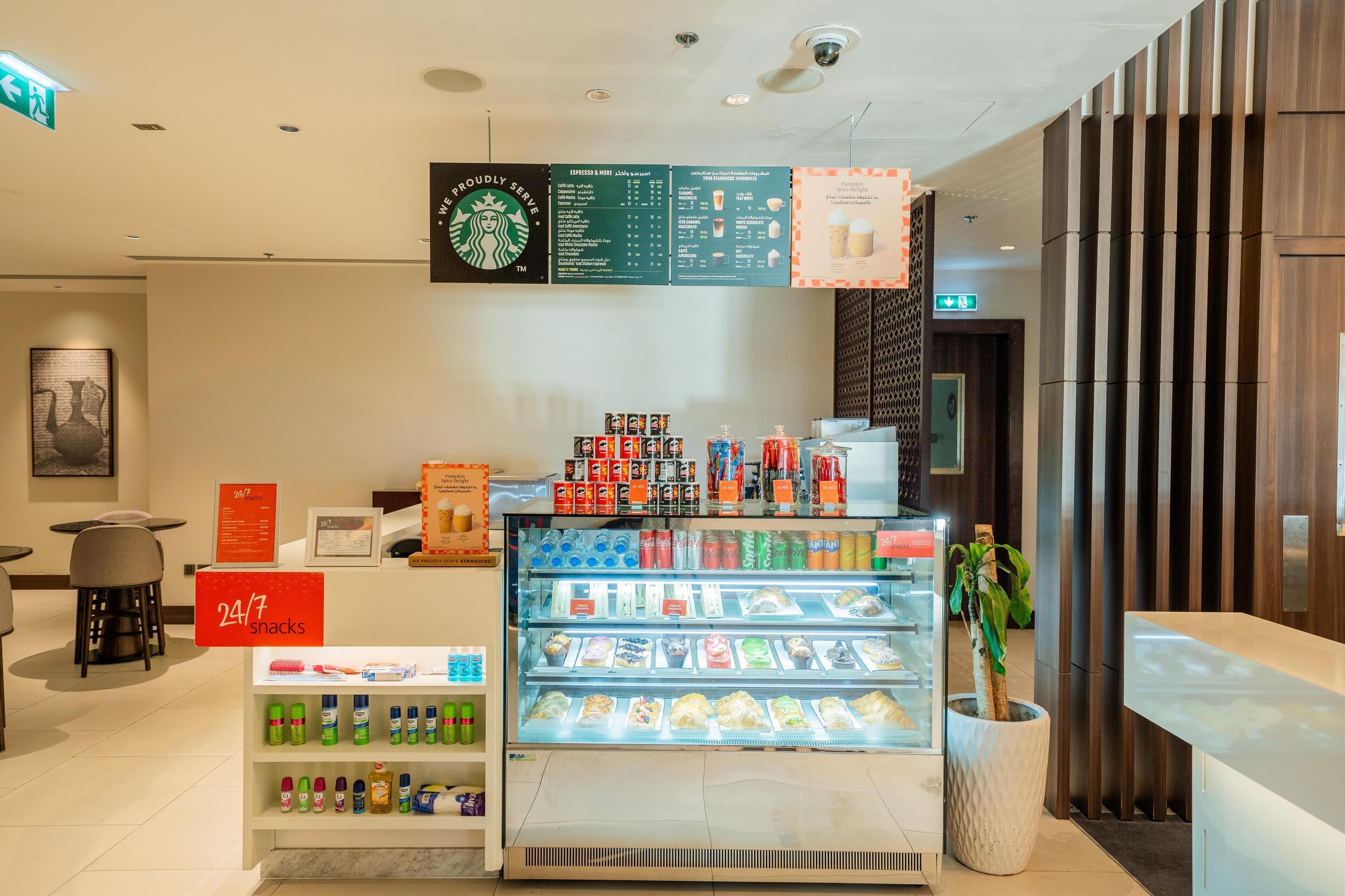 A Starbucks coffee shop interior with a refrigerated display case, snack shelves, and a menu board.