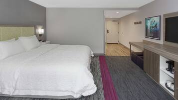 A hotel room with a large bed, a desk with a chair, a flat-screen TV, and a painting on the wall.