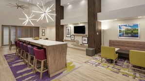 A modern hotel lobby with a bar area, seating, and artwork.