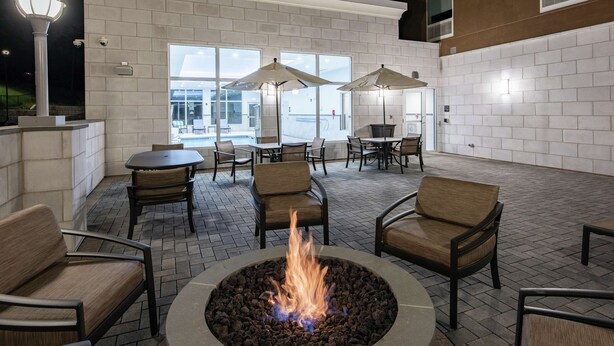 An outdoor patio area with a fire pit, seating, and umbrellas.