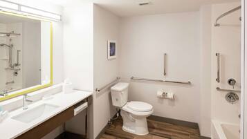 Un baño moderno con lavamanos, inodoro y zona de ducha blancos.
