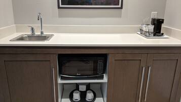 A compact kitchen with a sink, a microwave, and a coffee maker.