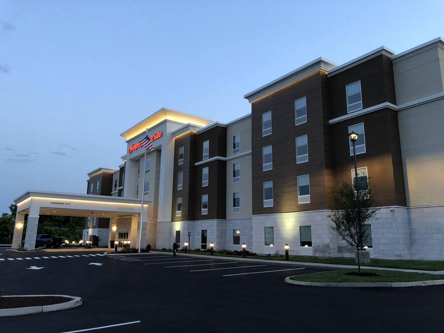 A modern hotel with a clear entrance, a flag, and a 'Welcome' sign.