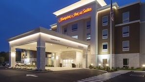 A Hampton Inn & Suites building with a clear entrance, a parking lot, and a flagpole.