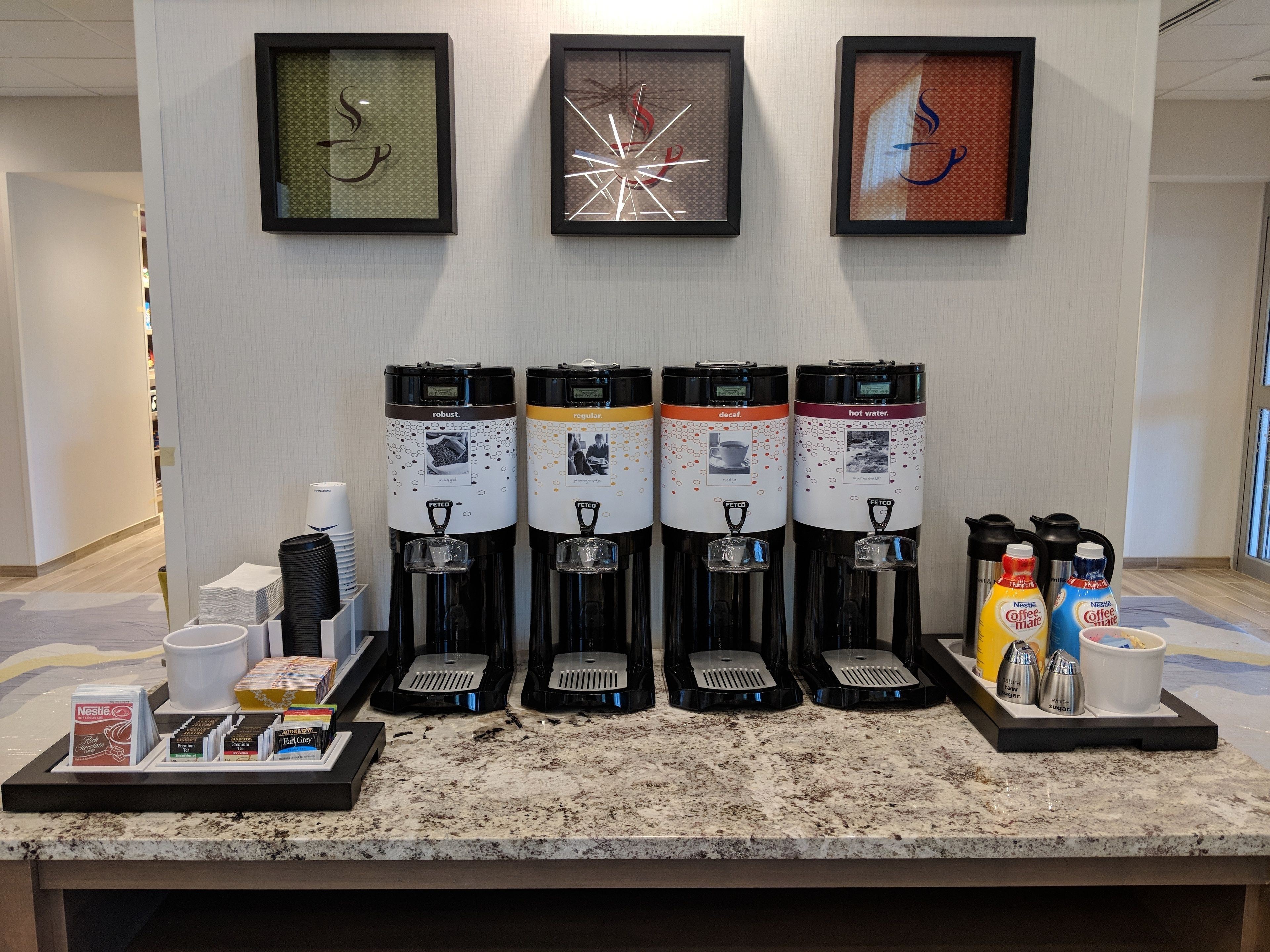 A coffee station with four dispensers labeled robust, regular, decaf, and hot water.