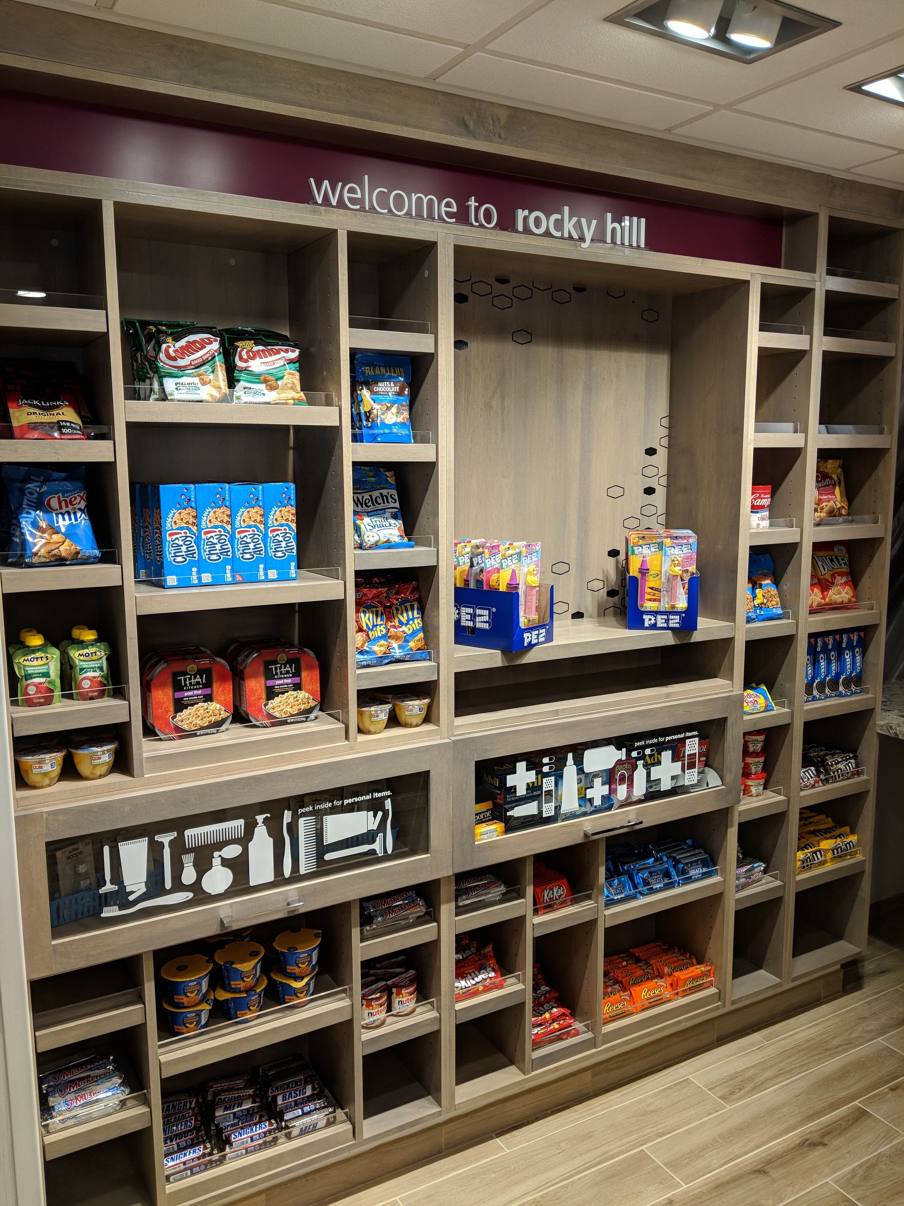 Un présentoir de produits d’épicerie dans un magasin, avec divers en-cas emballés et produits d’hygiène personnelle.