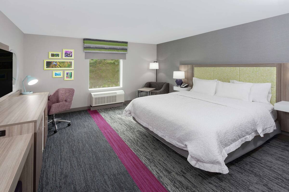 Una habitación de hotel con una cama grande, un escritorio, una silla, una mesita y una ventana.
