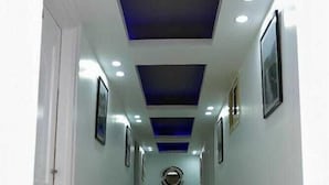 Un pasillo con piso pulido, iluminación empotrada y un detalle azul en el techo.