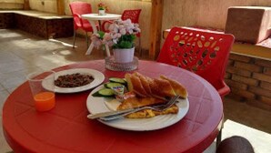 Una mesa redonda con comida, una planta en maceta y una silla roja.
