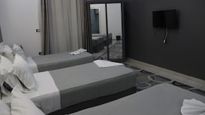 Habitación de hotel con dos camas individuales, un espejo grande, un televisor de pantalla plana en la pared y piso alfombrado.