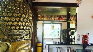 A Buddha statue in a dining area with a kitchen in the background. - Guest House da Lui (Ubatuba)